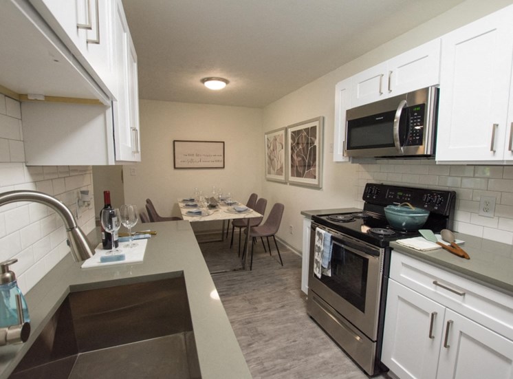 Cook in your gourmet kitchen at Icon Avondale. Stainless steal appliances, white cabinets, sink, oven, microwave, and dark wood like flooring.